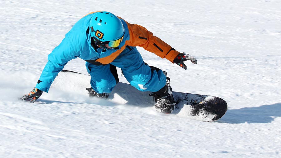 Snowboard ile dönüş hareketi yapan sporcu.